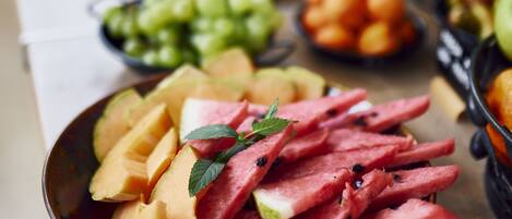 A buffet with various fruits and vegetables, including watermelon and cantaloupe.
