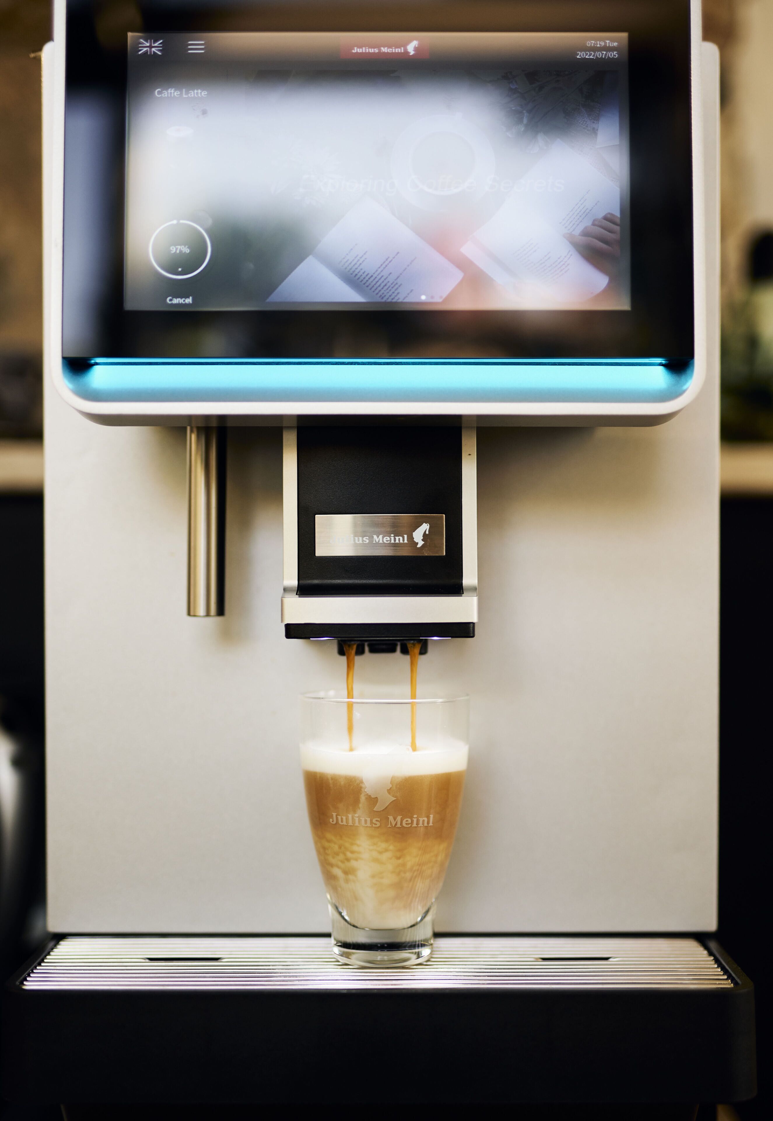 A coffee machine dispensing a latte into a glass.