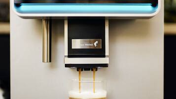 A coffee machine dispensing a latte into a glass.