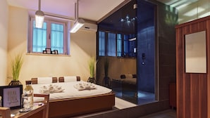 A modern bedroom with a large bed, bedside tables, a desk, and a view of a bathroom. - Hotel Villa Eugenia (Lovran)