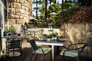 An outdoor patio with stone walls, tables, chairs, and potted plants. - Hotel Villa Eugenia (Lovran)