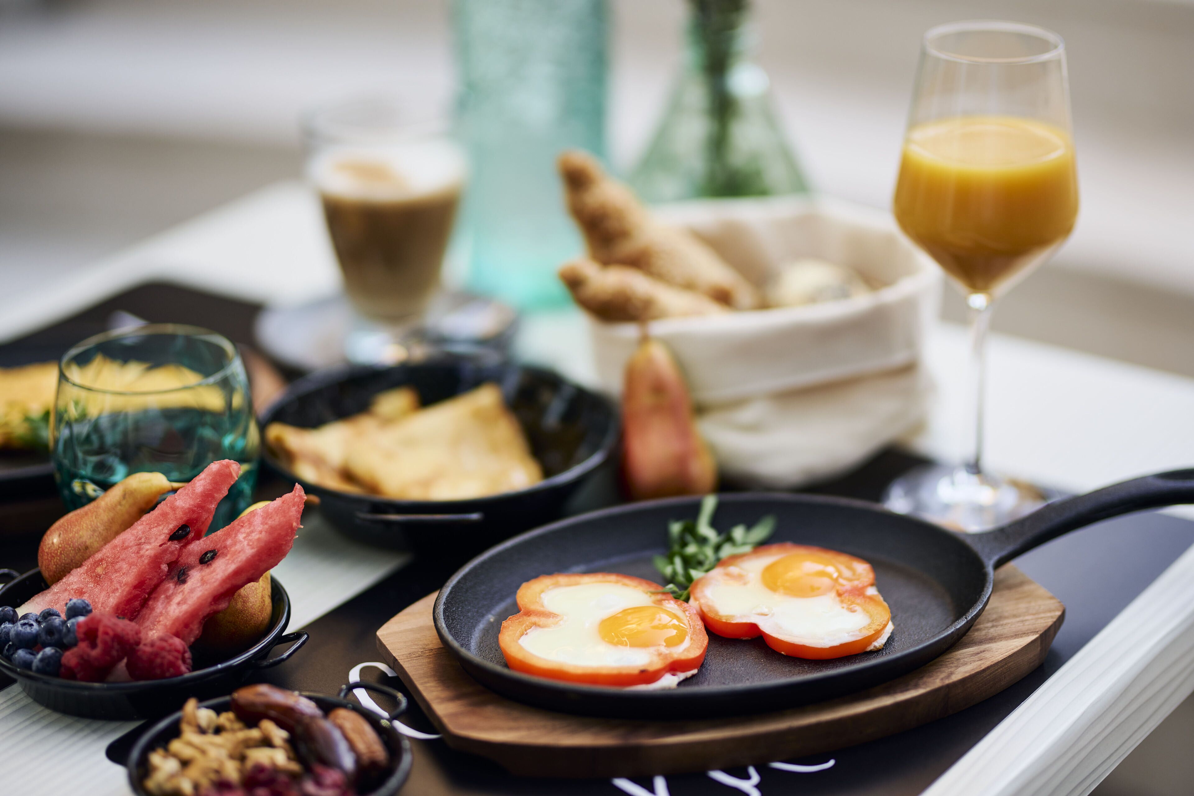 Ein Frühstücksbrett mit Eiern, Tomaten, Obst und Gebäck.