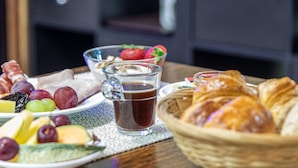 A breakfast table with fruits, pastries, and a beverage. - Will's Hotel (Narbonne)