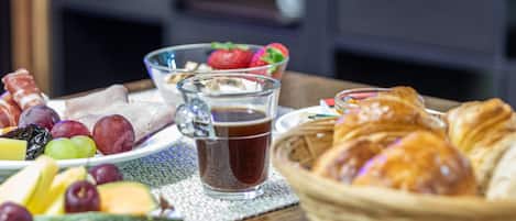 Mesa de café da manhã com frutas, doces e uma bebida.