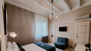 A bedroom with two beds, a chair, a TV, and a wardrobe. - Will's Hotel (Narbonne)