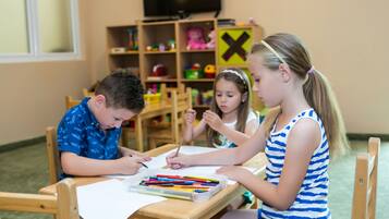 Children learn and create in this well-equipped classroom with desks, chairs, and educational materials.