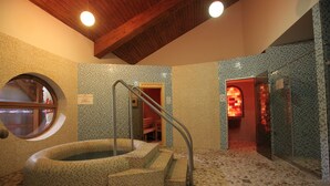 A spa area with a hot tub, tiled walls, and a wooden ceiling. - Colosseum Hotel Mórahalom (Morahalom)
