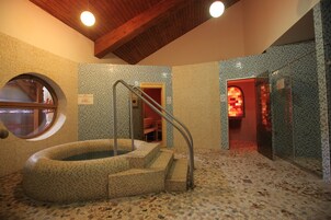 Un área de spa con hidromasaje, paredes con azulejos y techo de madera.
