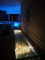 Zona de piscina con un paseo bordeado de piedras y una decoración de pared con forma de estrella.