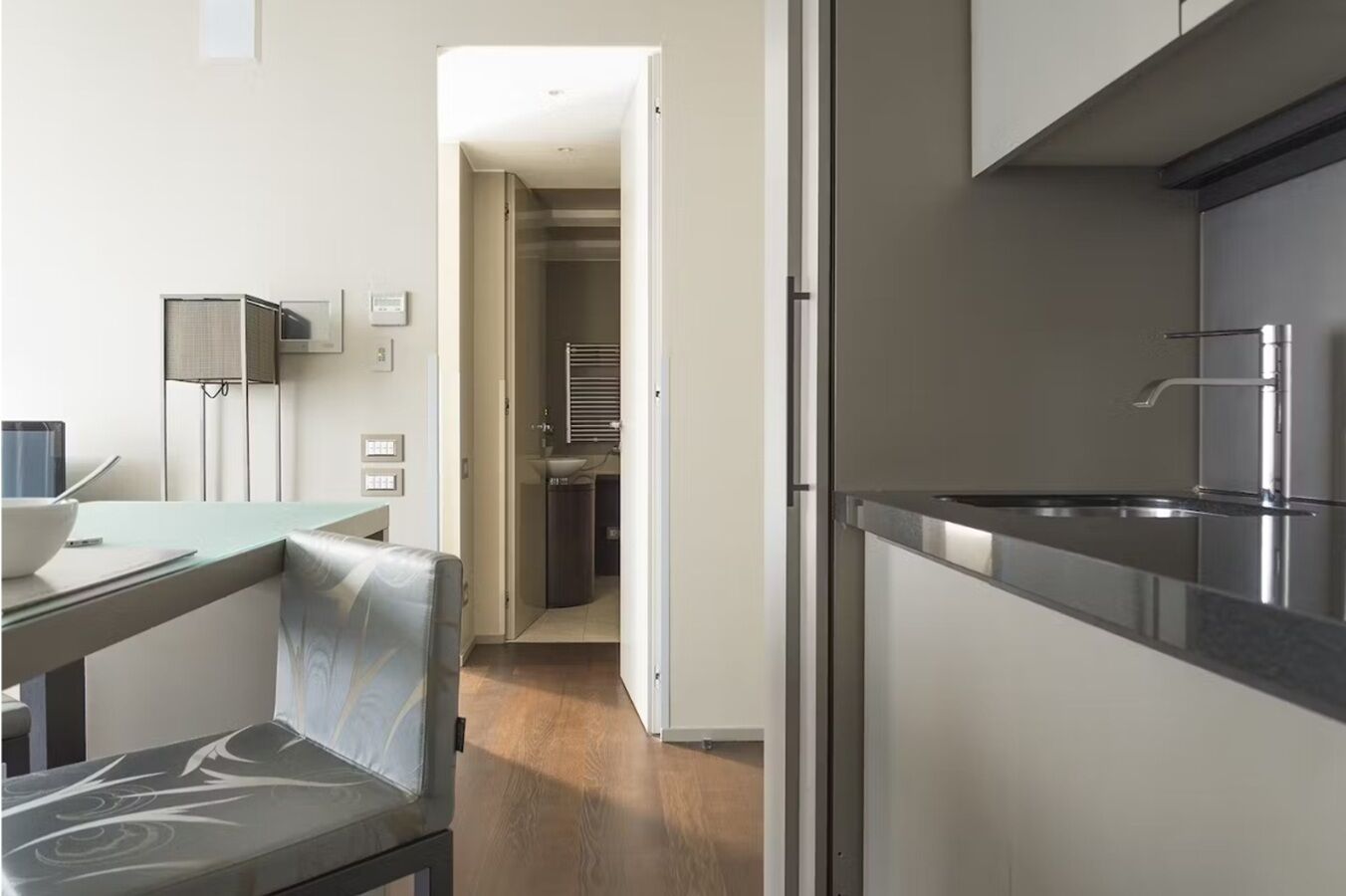 Una cocina moderna con horno empotrado, pileta de acero inoxidable y comedor con mesa y silla.