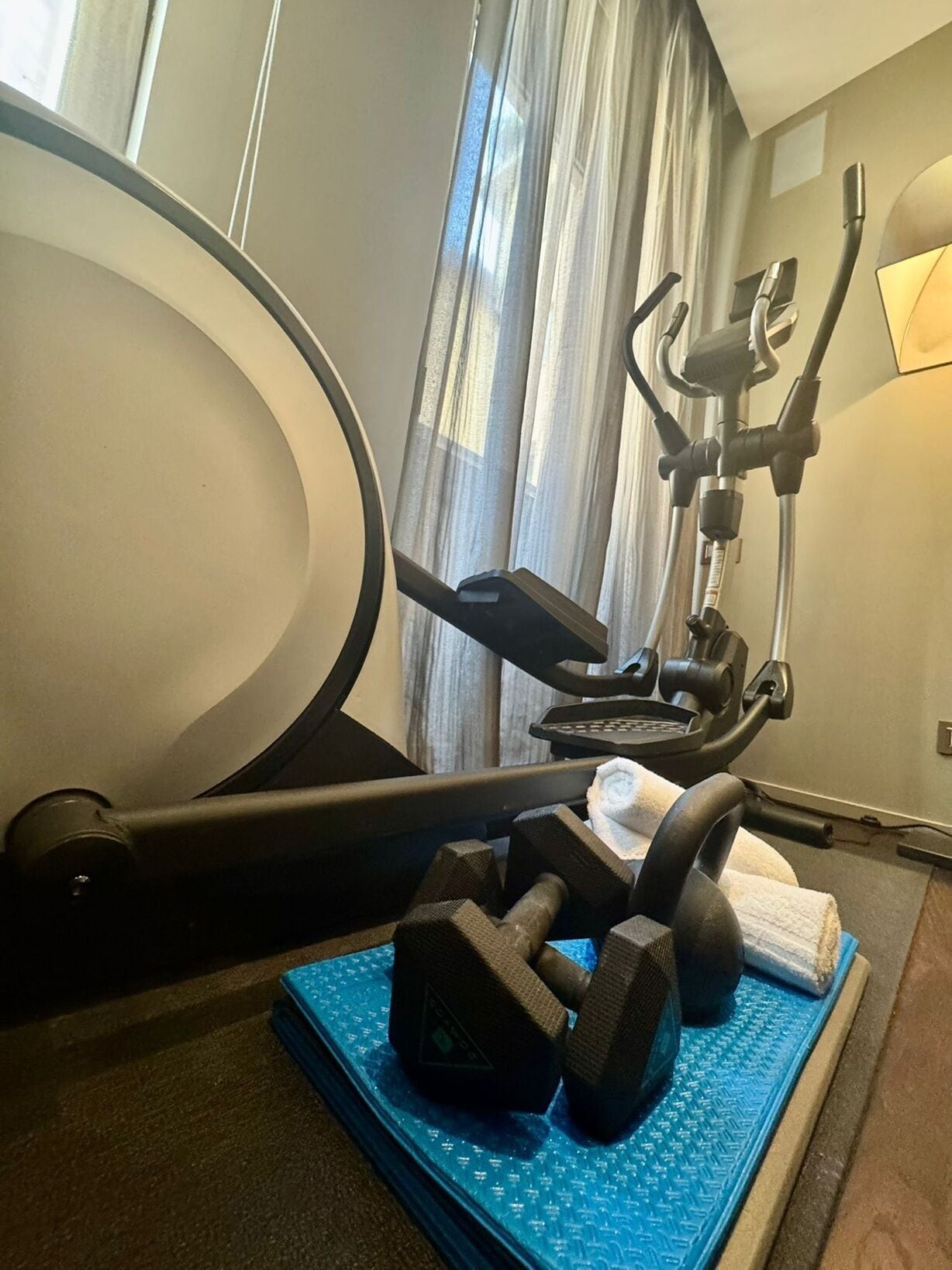 Un gimnasio en casa con equipo de ejercicio, incluyendo una máquina de remo, mancuernas y una toalla.