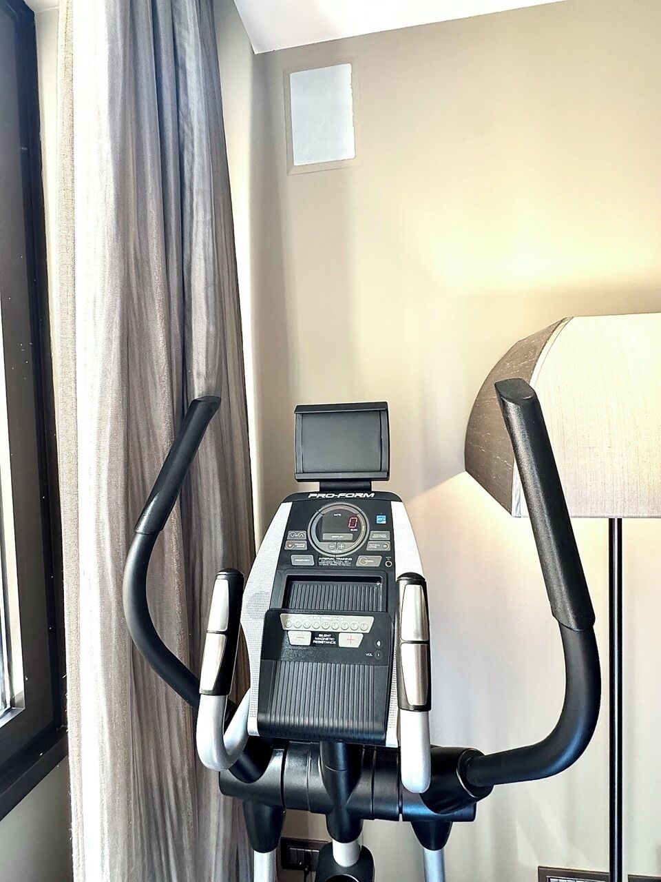 Une pièce équipée d’un tapis de course, d’un petit écran et d’une lampe.