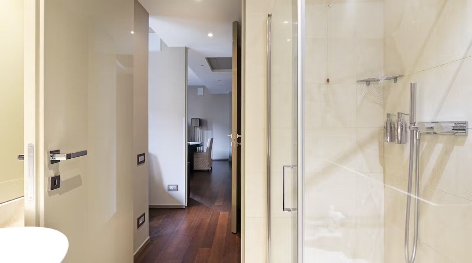 A modern bathroom with a glass shower enclosure, a toilet, and a sink.
