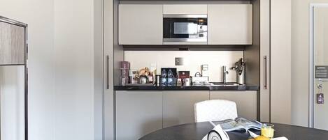 A compact kitchen with a microwave, coffee maker, and a small refrigerator.