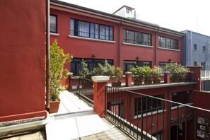 A red building with multiple windows and balconies, some with potted plants. - Oasi Village Hotel (Milan)