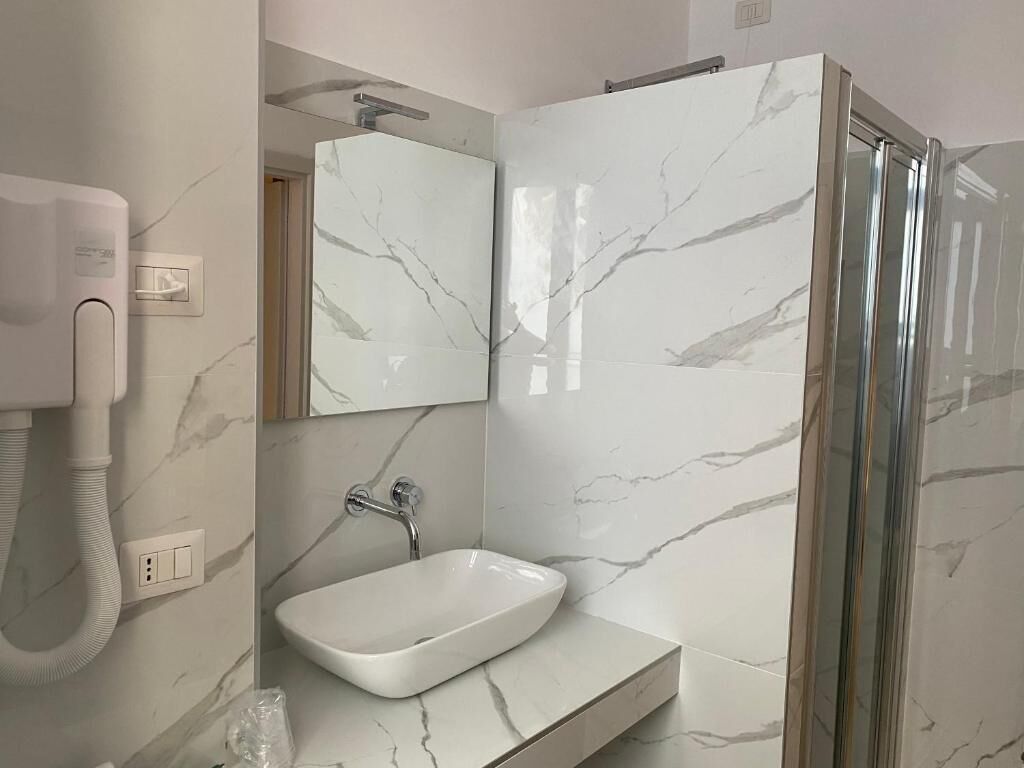 A bathroom with a white sink, a mirror, and a shower enclosure.