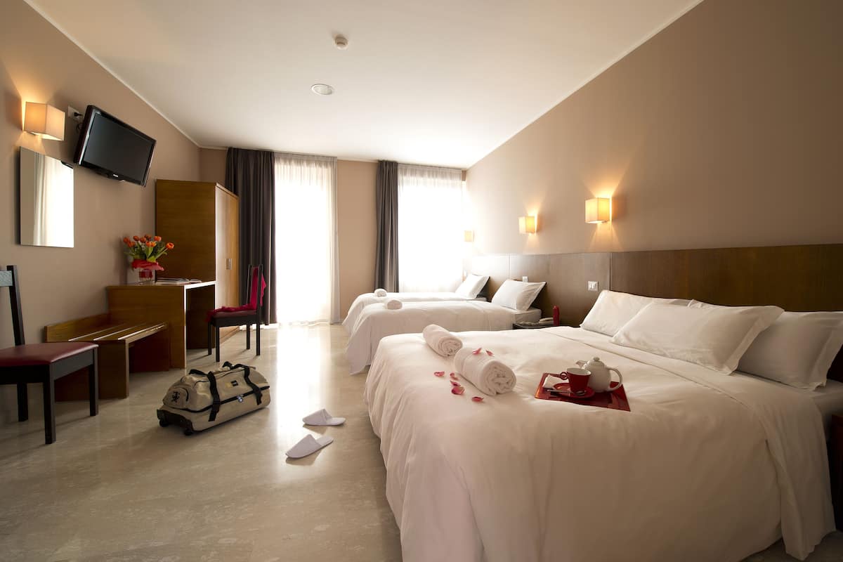 A hotel room with two beds, a TV, a desk, and a chair.