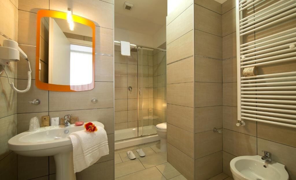 A bathroom with a sink, mirror, shower, and toilet.