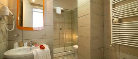 A bathroom with a sink, mirror, shower, and toilet.