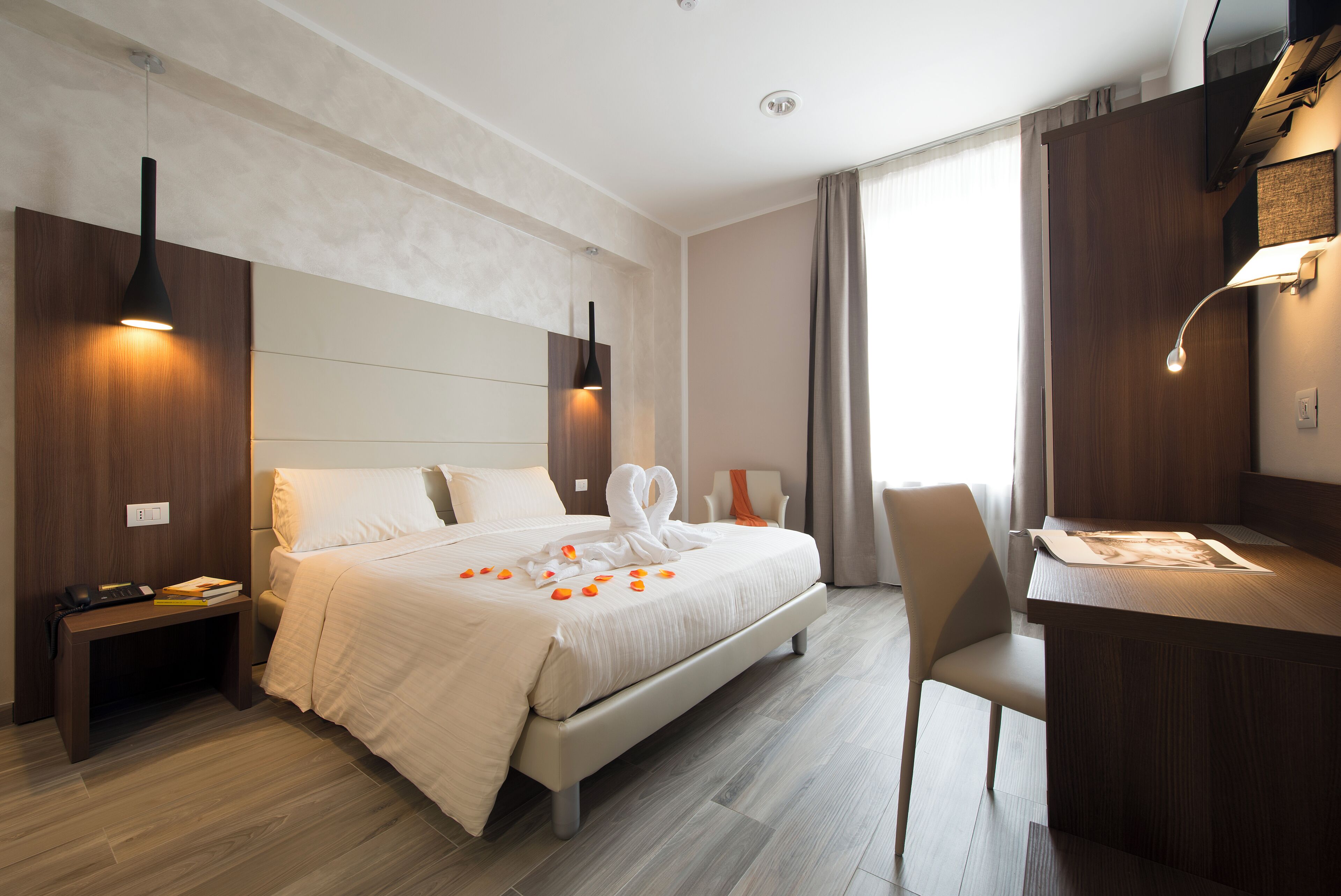 A modern hotel room with a large bed, bedside tables, a desk, and a chair.