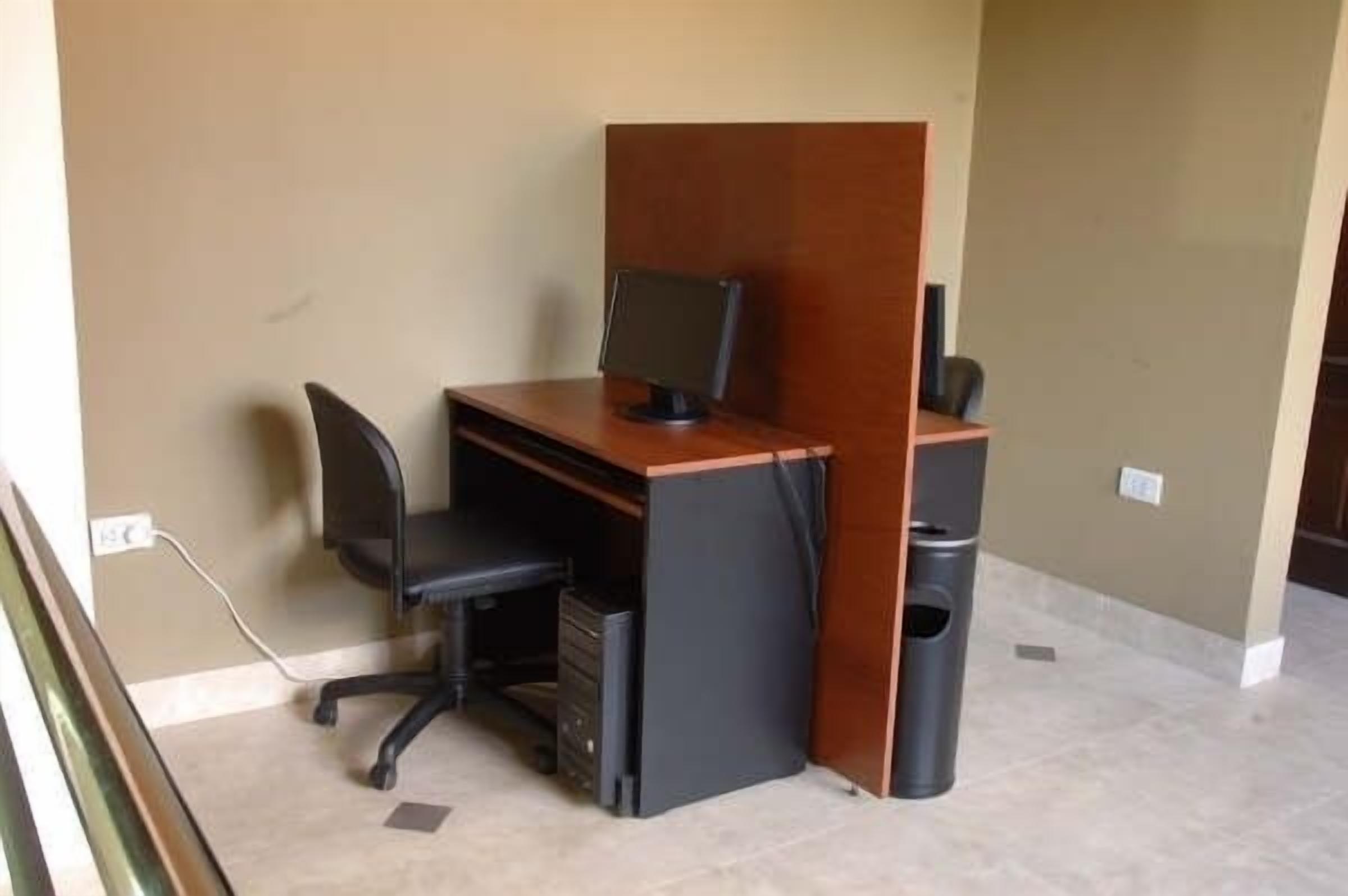 A small office space with a desk, chair, computer, and trash can.