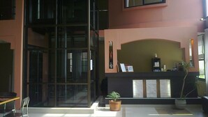 A lobby with a reception desk, a large glass wall, and potted plants. - Hotel Boutique Aybal (Salta)