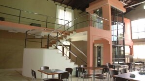 A multi-level dining area with tables and chairs, a staircase, and a glass railing. - Hotel Boutique Aybal (Salta)