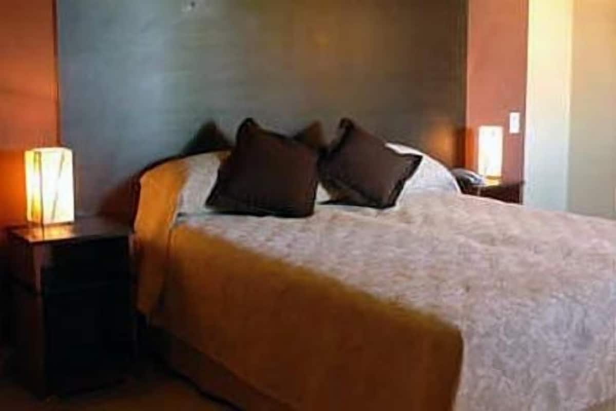 A neatly made bed with a duvet, two pillows, and a bedside table with a lamp.