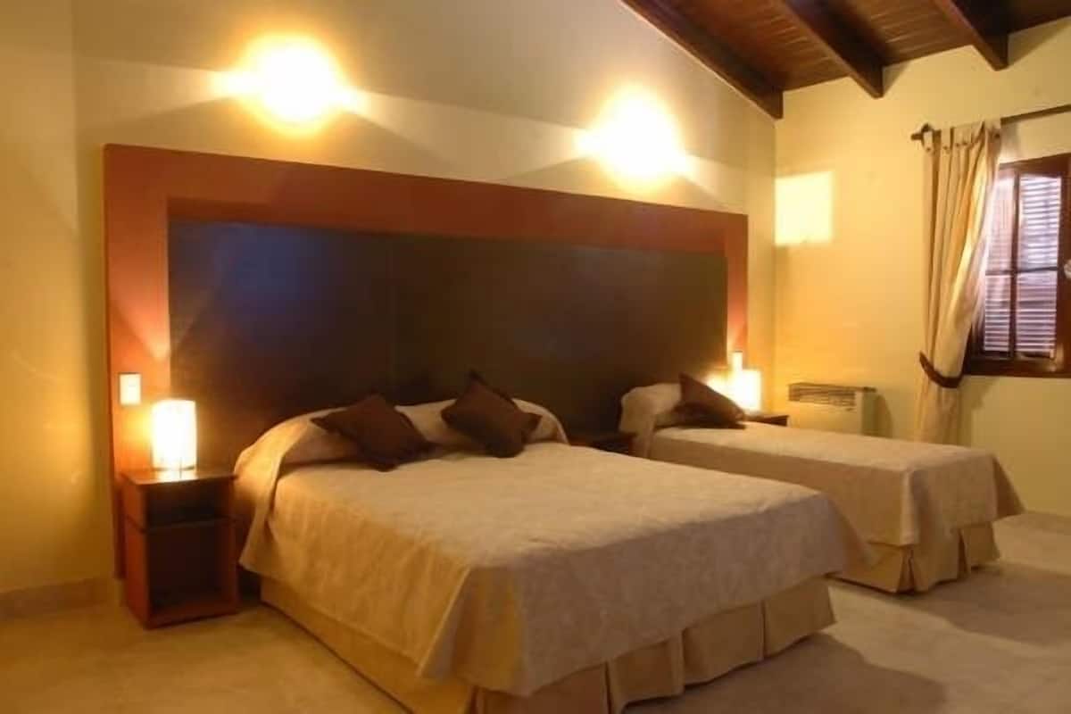 A room with two beds, each with a wooden headboard and bedside lamps.
