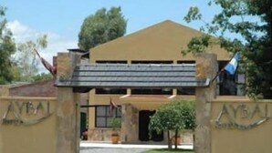 A building with a beige facade, a sloped roof, and a flag on the right. - Hotel Boutique Aybal (Salta)