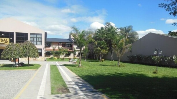 A building with a sign reading "BAL" and a well-maintained lawn with trees and a pathway. - Hotel Boutique Aybal (Salta)