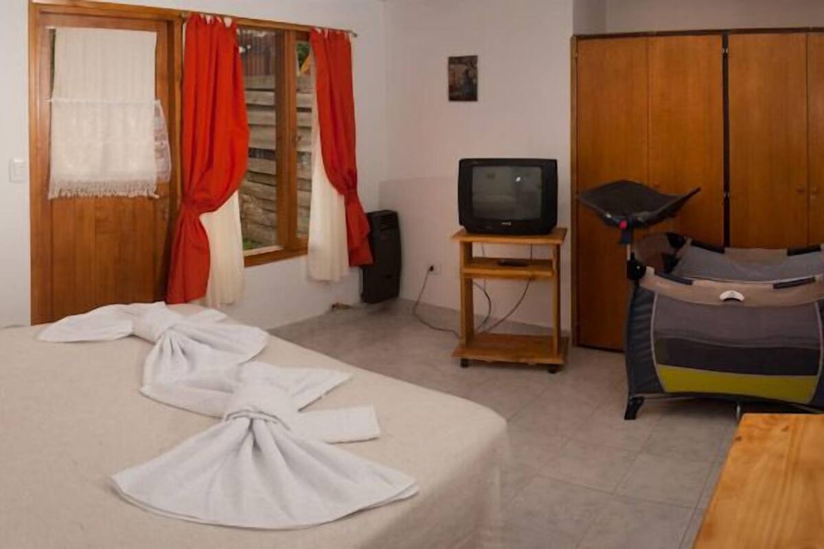 A room with a bed, a television, a wardrobe, and a baby stroller.