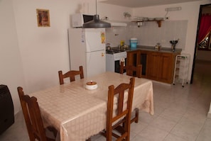 Una cocina compacta con una mesa de comedor, sillas, un refrigerador, estufa y un microondas.