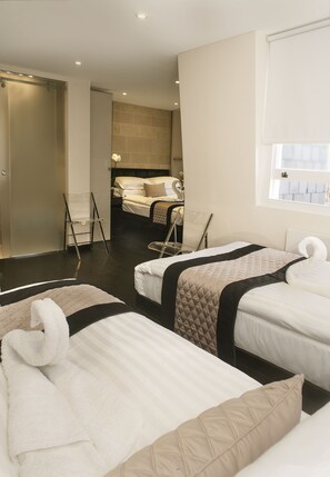 A hotel room with two beds, a small seating area, and a view of the city. - NOX HOTELS - Notting Hill (London)