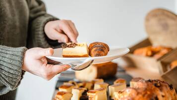 En person som håller i en tallrik med ett bakverk och en bit cheesecake.