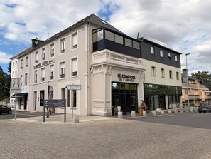 A hotel with a classic facade, a modern entrance, and a sign indicating a restaurant nearby.