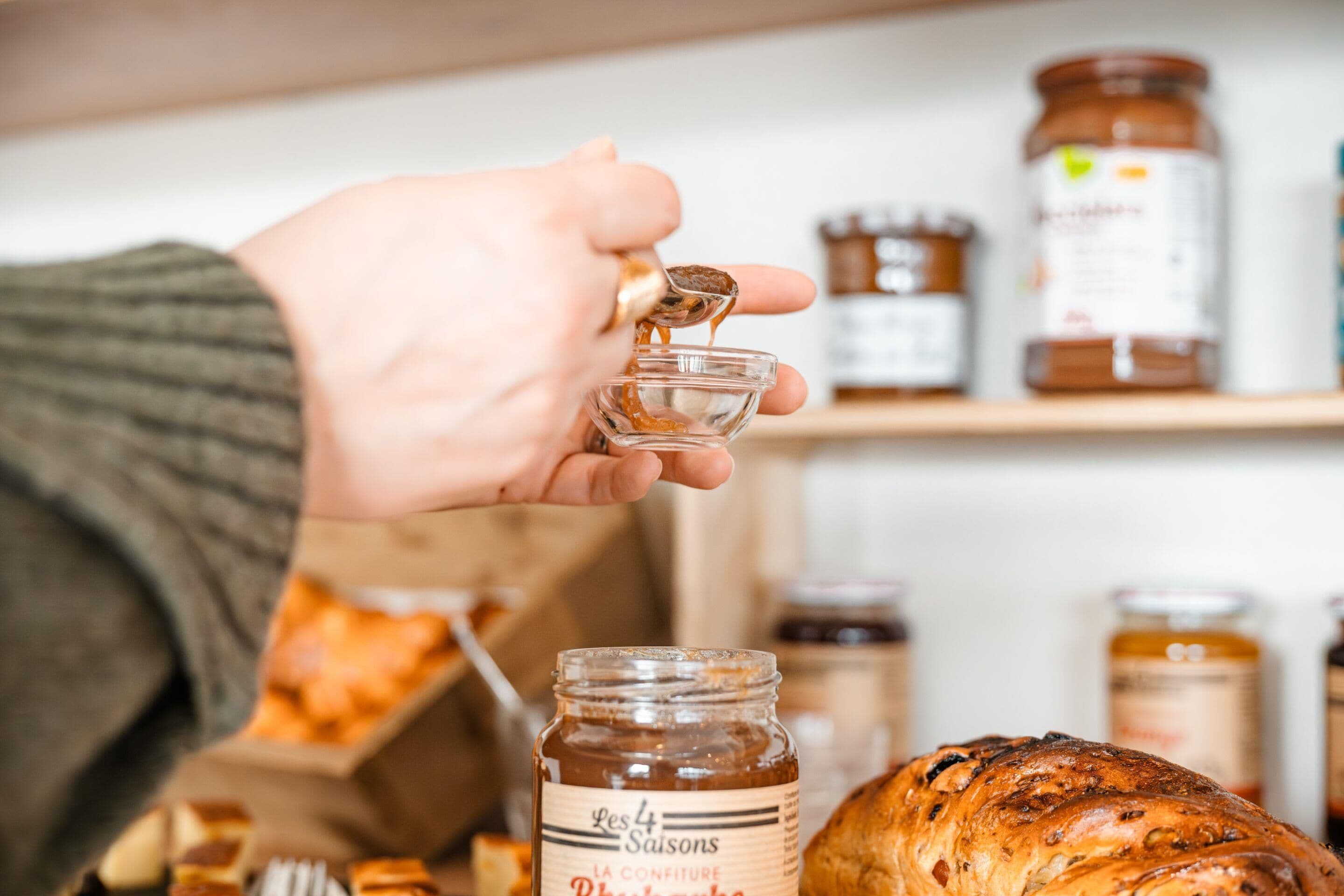 A hand squeezing honey from a jar into a glass.