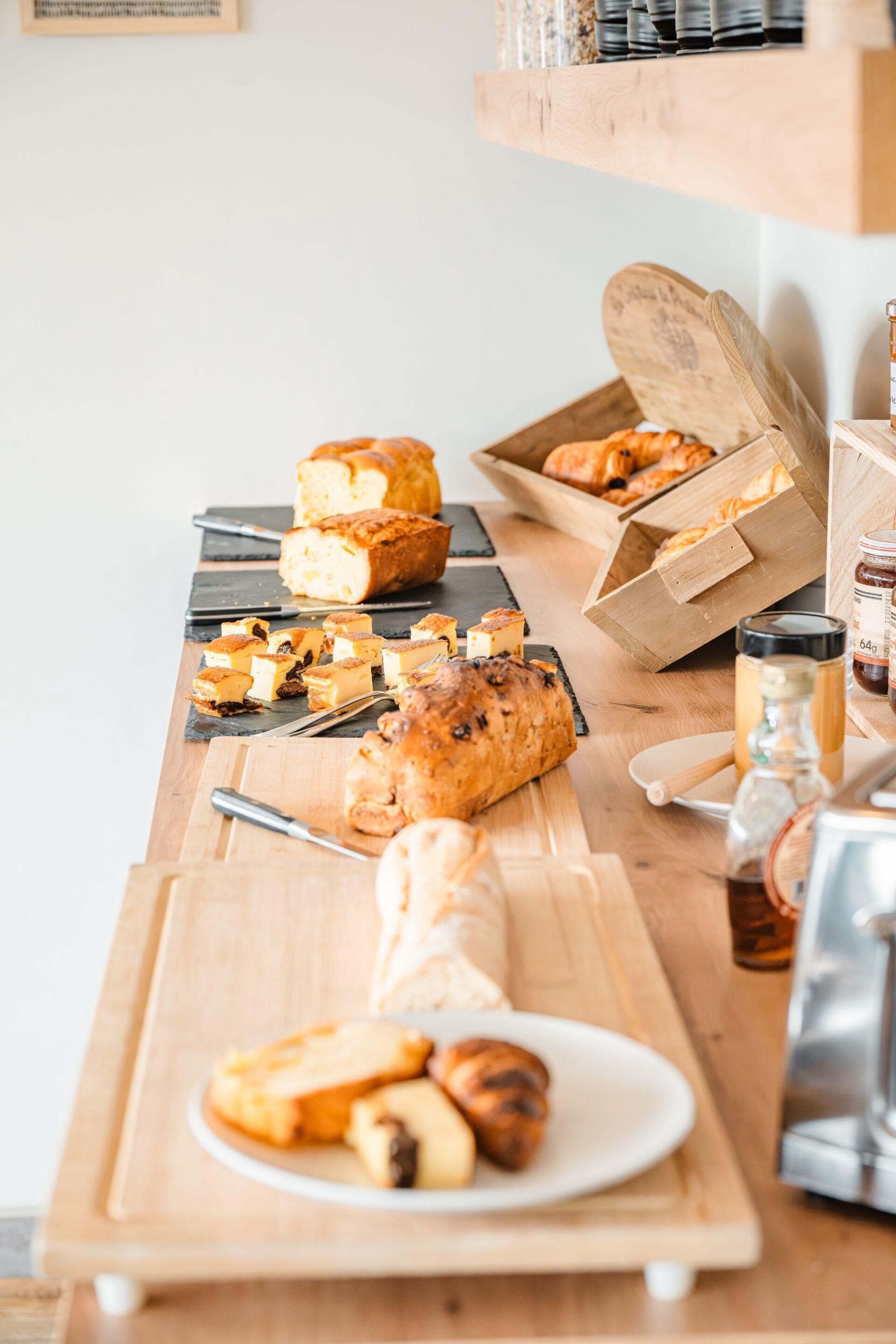 A wooden table with various baked goods, including bread and pastries.