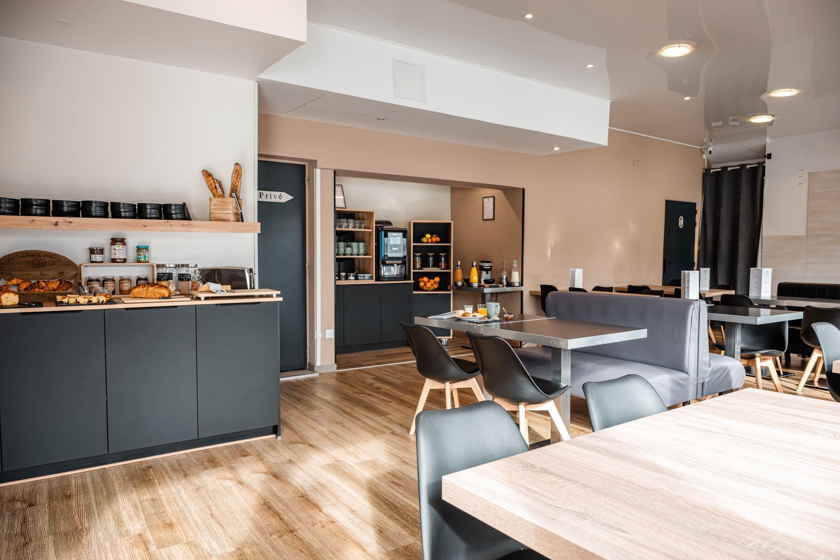 A modern restaurant with a bar area, seating, and a kitchen visible in the background.