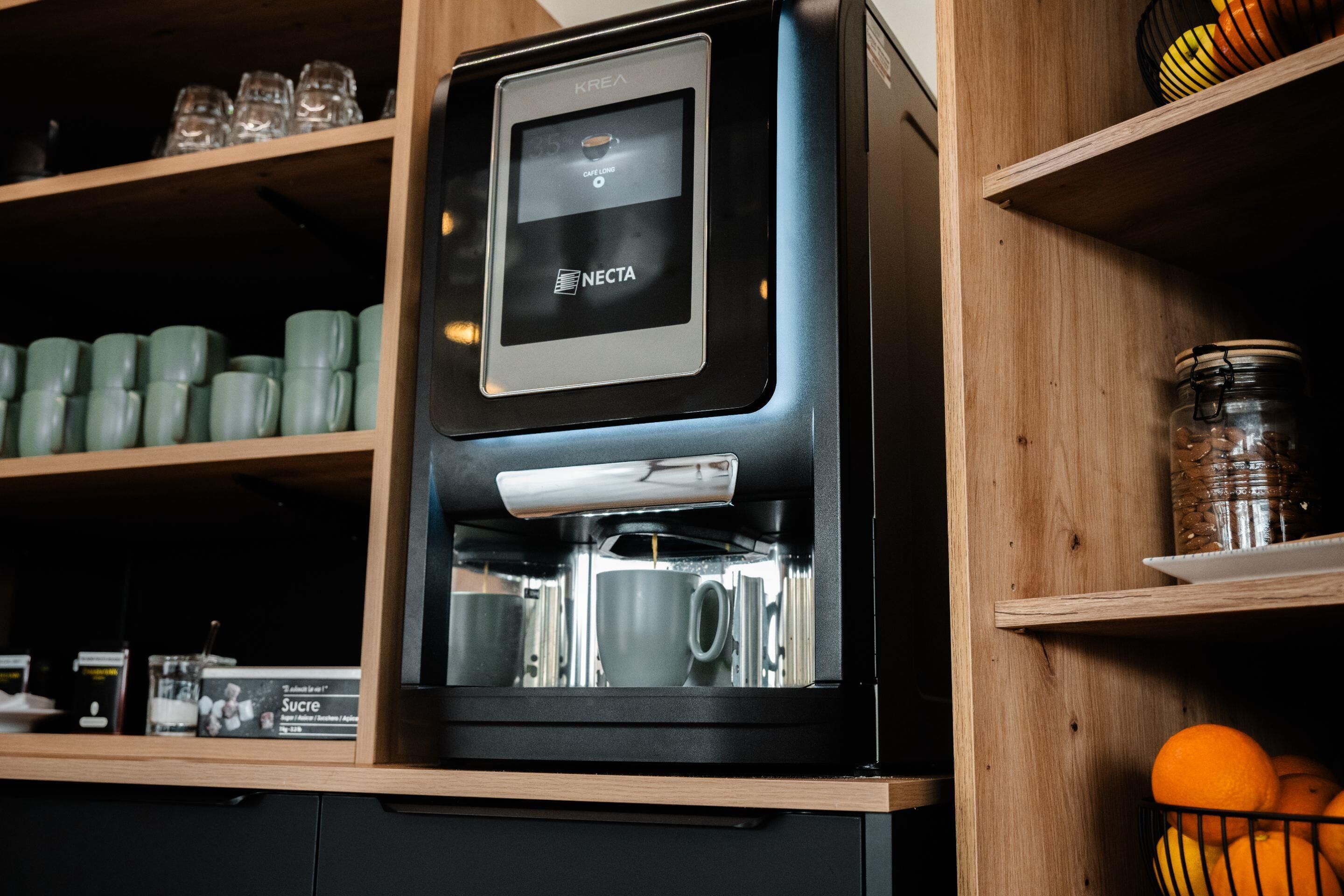 A coffee machine with a digital display and a coffee pot inside a wooden cabinet.