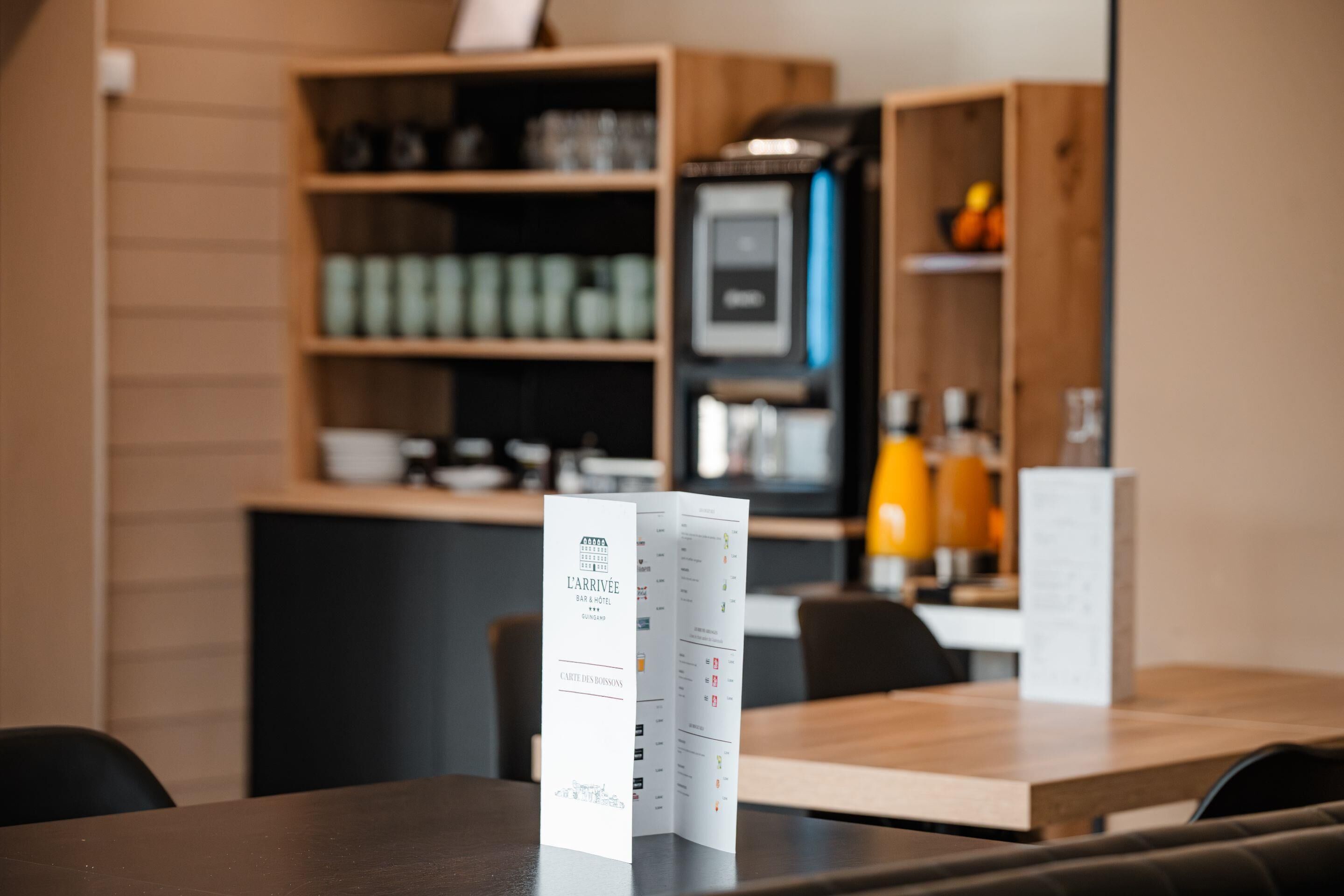 A restaurant interior with a menu stand, wooden shelves with items, and a coffee machine.