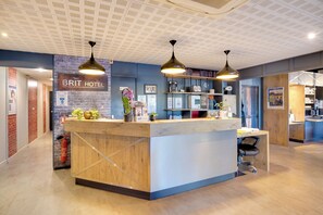 Un mostrador de recepción con detalles de madera, una pared de ladrillo y un cartel que dice 'BRIT HOTEL'.