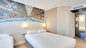 Ein Hotelzimmer mit einem großen Bett, einem Nachttisch, einer Wandleuchte und einer Tür zum Badezimmer.