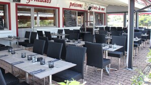 An outdoor restaurant with tables and chairs, a menu board, and a sign reading "grillades poissons fruits de mer". - Brit Hotel La Rochelle Périgny (Perigny)