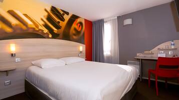Ein Hotelzimmer mit einem großen Bett, einem Schreibtisch mit Stuhl und einer Wandlampe.