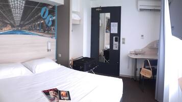 Habitación de hotel con una cama grande, un escritorio, una silla, un televisor y una pared con un mural.