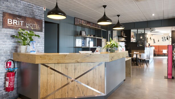 A reception area with a wooden counter, a sign reading "BRIT HOTEL", and a fire extinguisher. - Brit Hotel La Rochelle Périgny (Perigny)