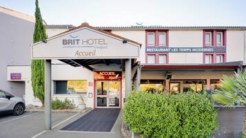 A hotel entrance with a sign for 'BRIT HOTEL Accueil' and a restaurant named 'RESTAURANT LES TEMPS MODERNES OPEN'.
