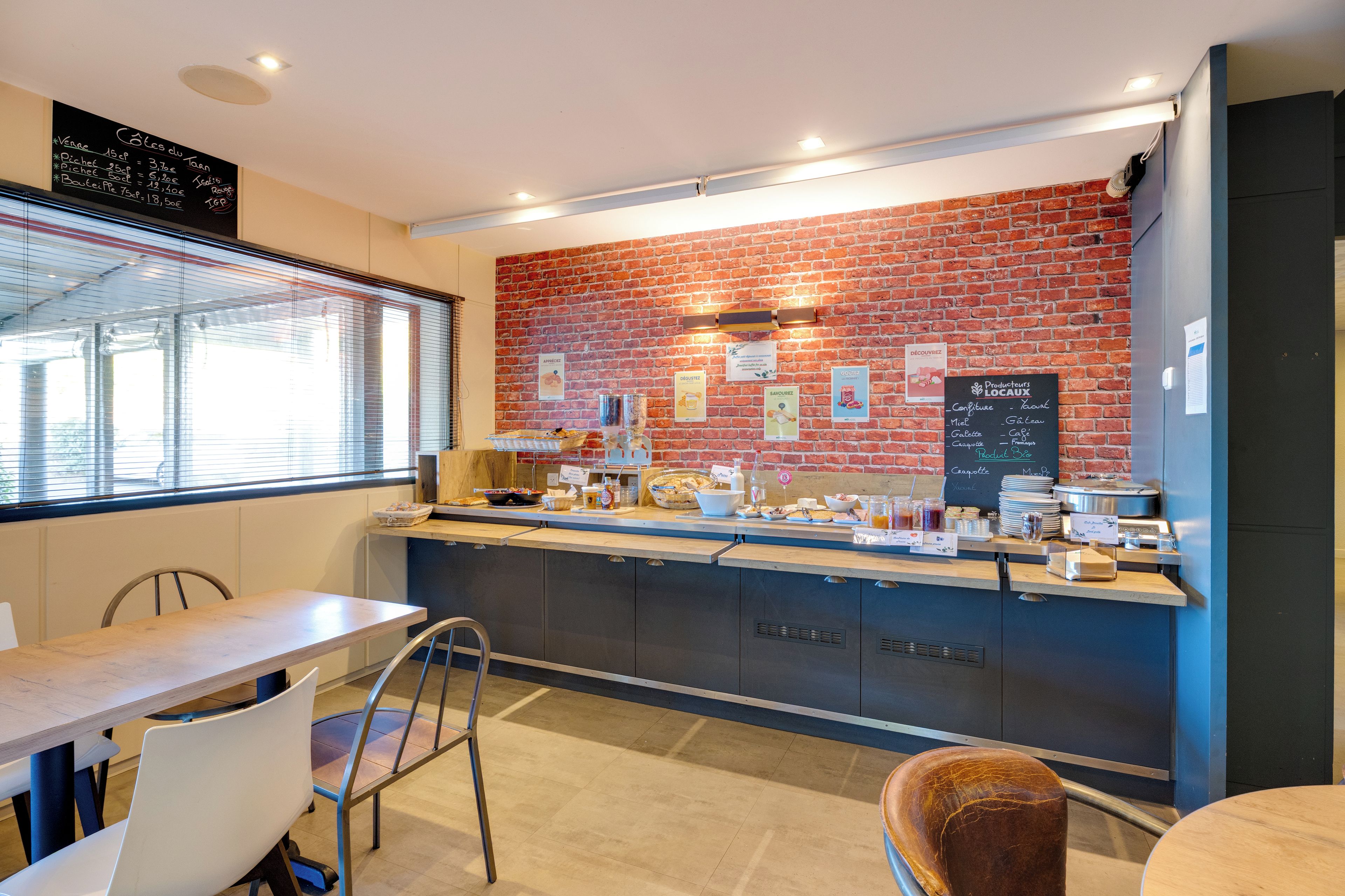 A cafe with a brick wall, a menu board, and a counter with food and drinks.