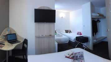 Habitación de hotel con escritorio, computadora portátil, cama, televisión y vestidor.
